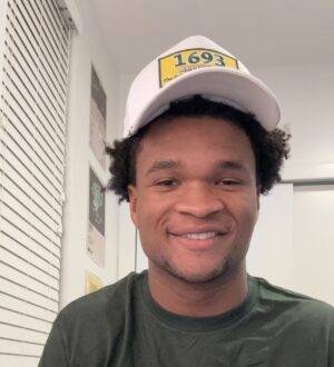 Chase Lowe smiles at the camera wearing a 1693 Alliance t shirt and hat