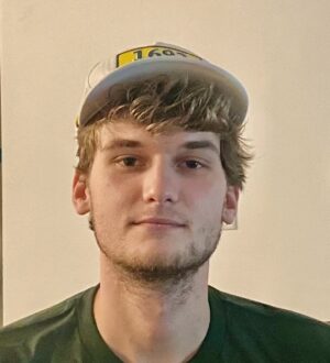 Finn Lally wears a green and yellow 1693 Alliance shirt and baseball cap