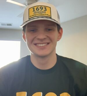 Kyle Frazier smiles at the camera wearing a 1694 shirt and hat